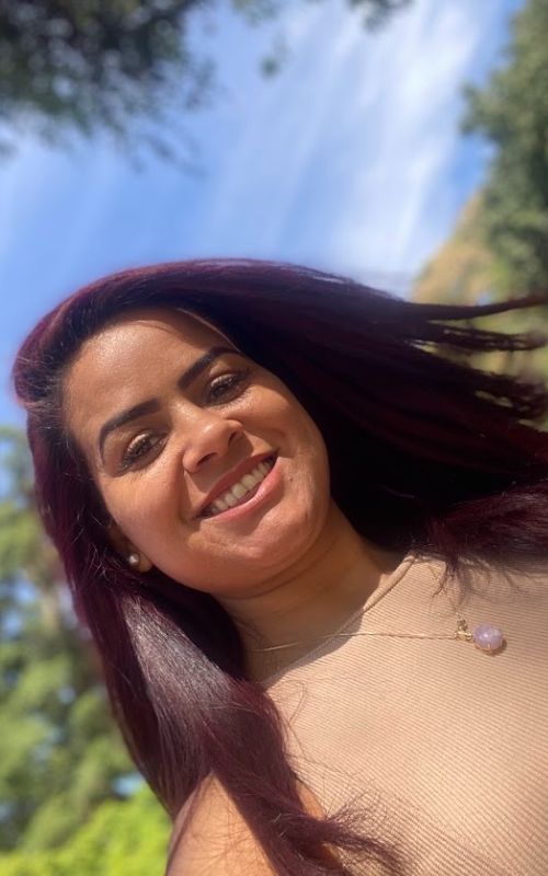 Mulher sorrindo para a câmera, com cabelos longos.